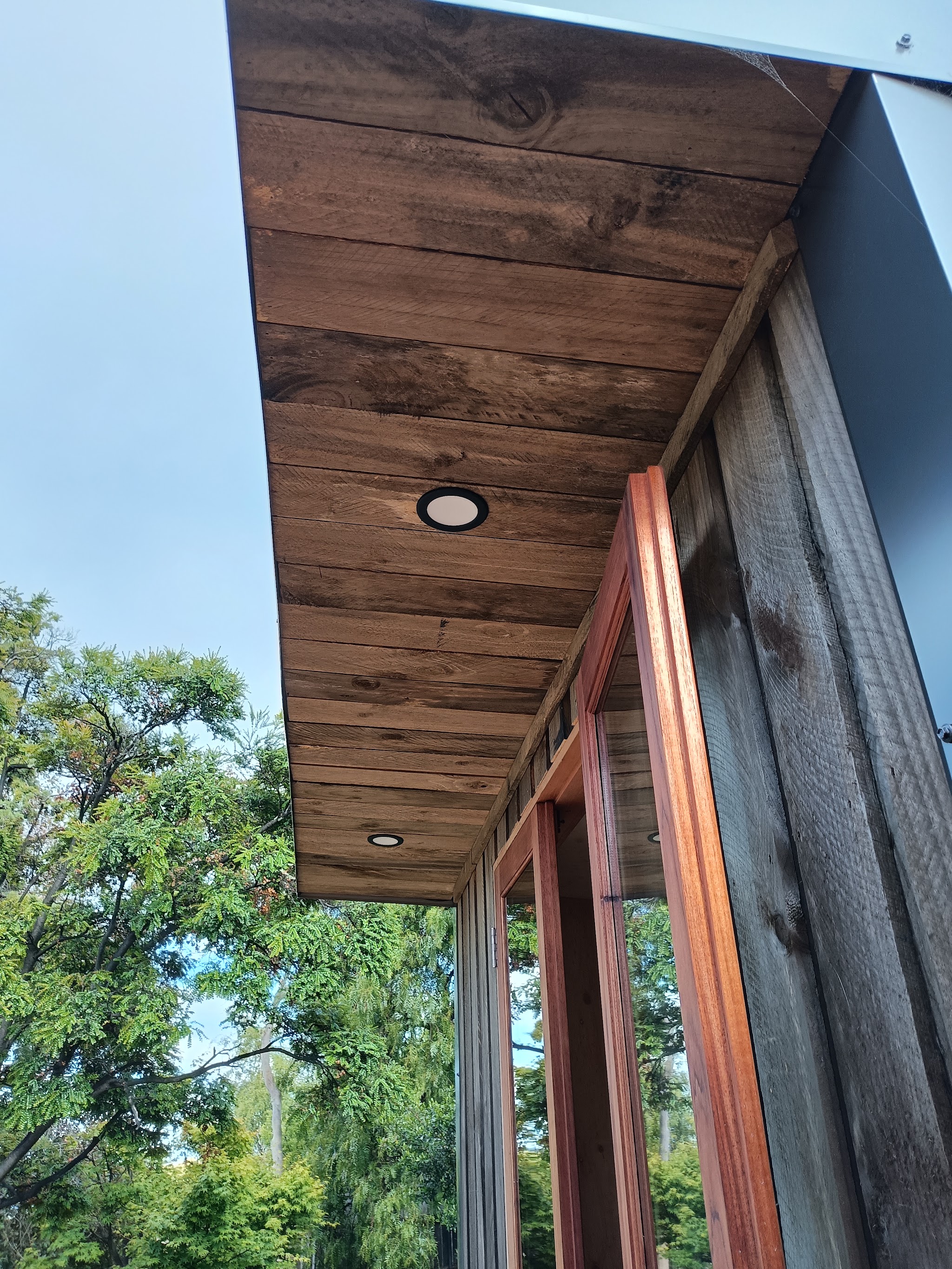 Two recessed downlights installed in a timber eave ceiling above timber-framed doors